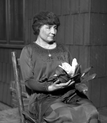 A negyven év körüli Helen Keller egy virág szépségét élvezi