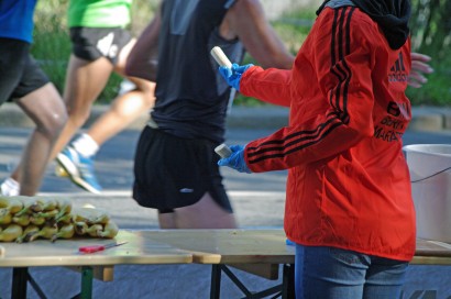 Egy önkéntes banánt ad a futóknak – egy önkéntes ad a futóknak banánt